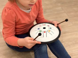 Enfant qui joue du tongue drum coloré